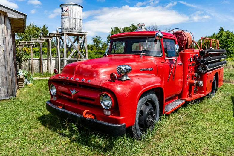 an old red truck parked in the grass