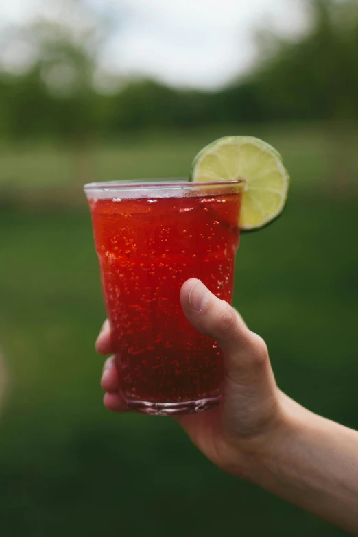 a hand holding a drink up close to the camera