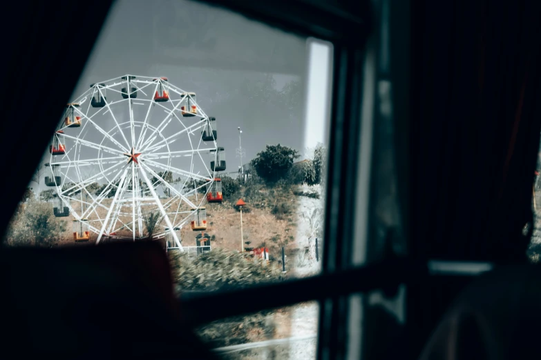 a ferris wheel and trees seen through a window