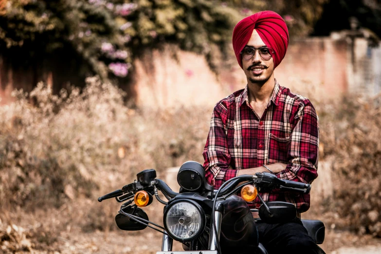 a man sitting on top of a motorcycle with a turban on