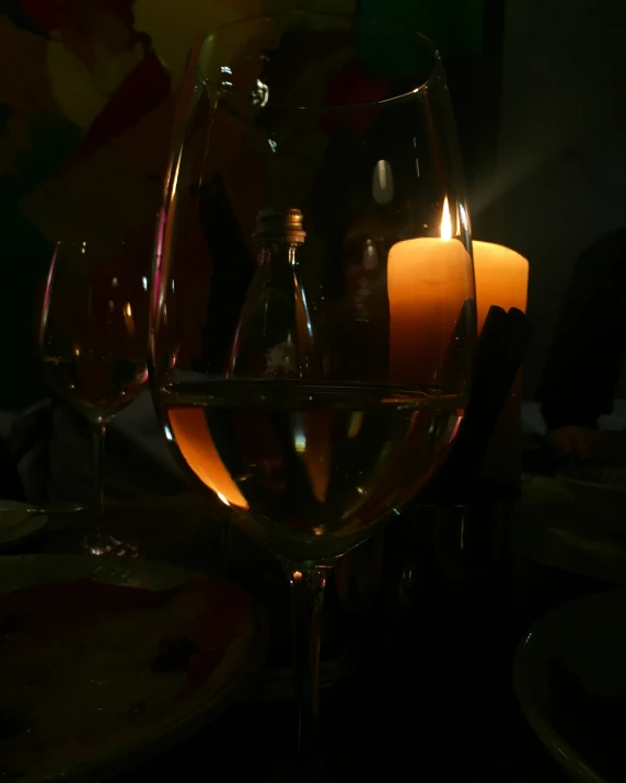 the lit candle is between two glasses of wine