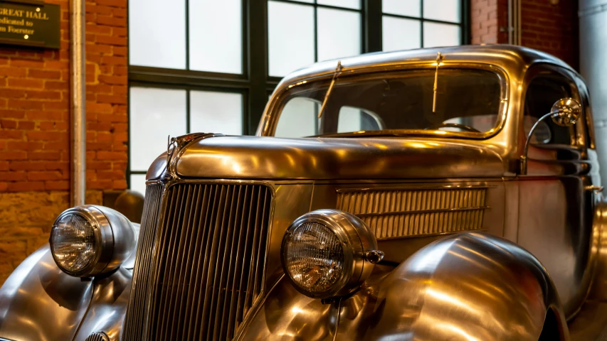 a shiny, metal antique car parked inside of a building