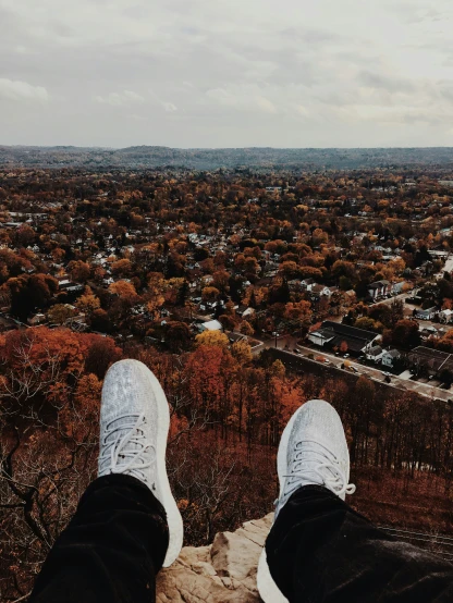 person's feet with view of city from a viewpoint