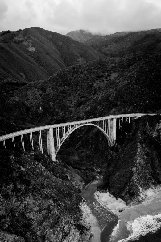 a view from the air of a bridge over a river in a mountainside area