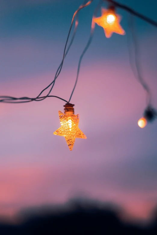 some string lights hanging in front of a twilight sky