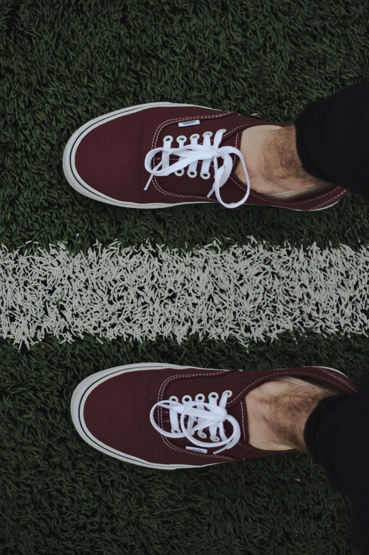 two people in shoes are standing on grass