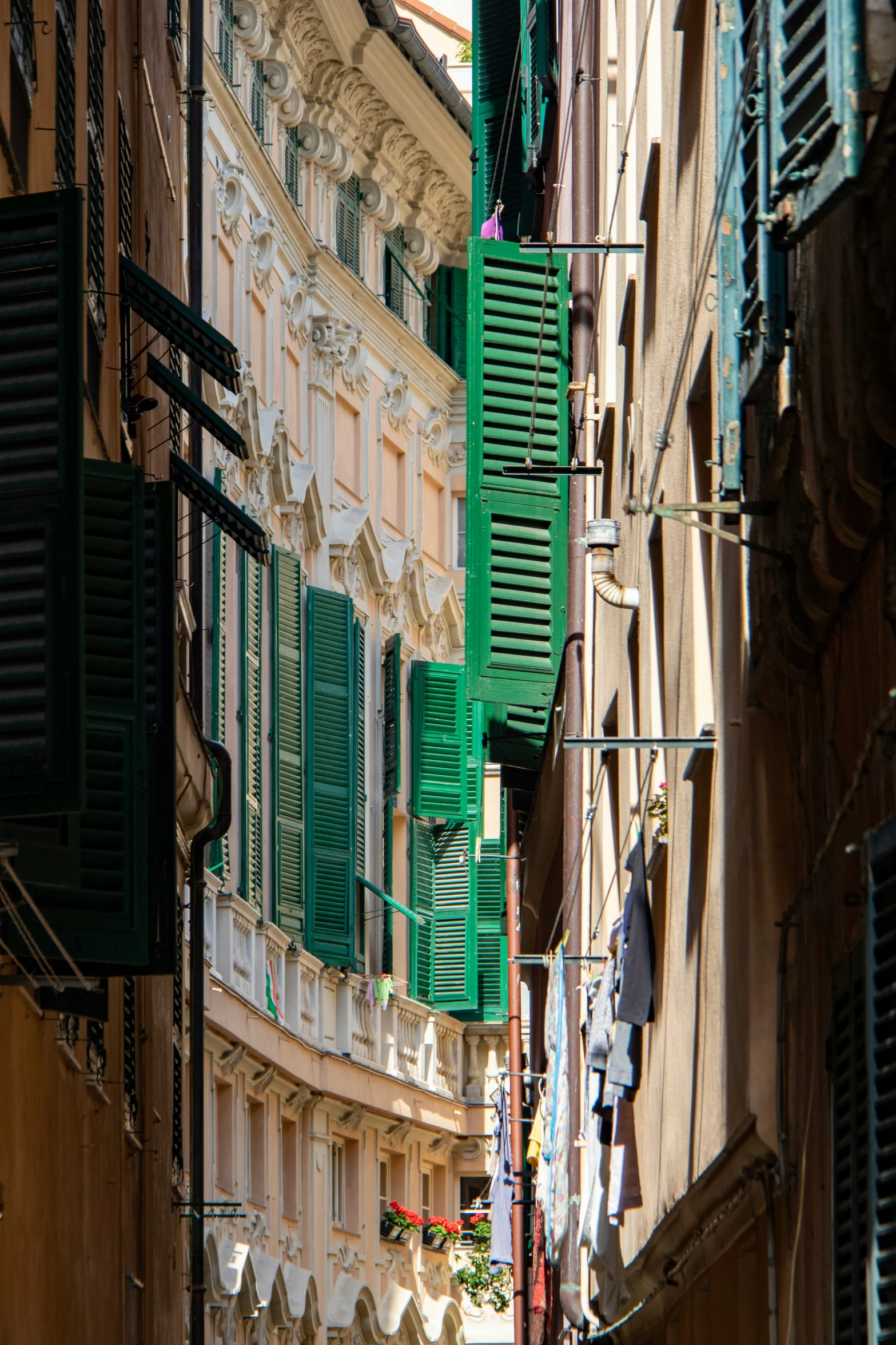 an alley way with several different buildings and green shutters