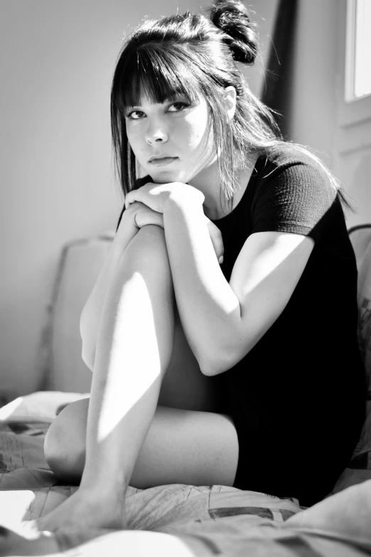 a woman sitting down on a bed and looking forward