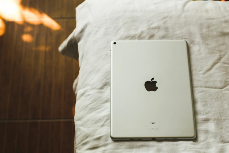 an ipad sitting on a bed next to the pillow