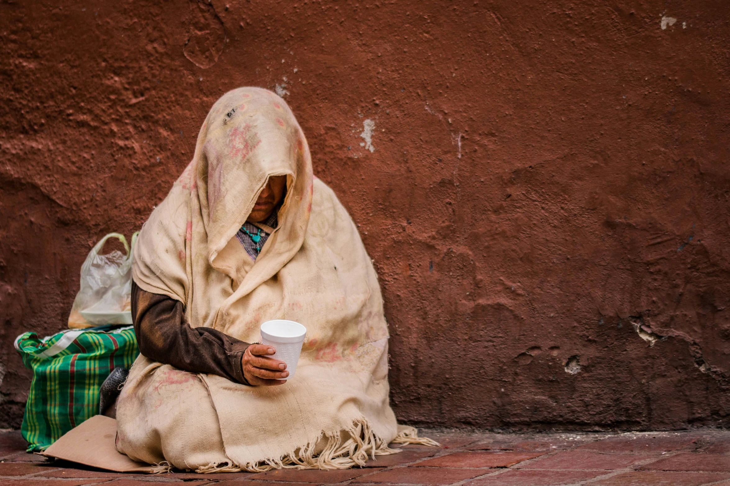 a woman in a scarf is sitting on the street