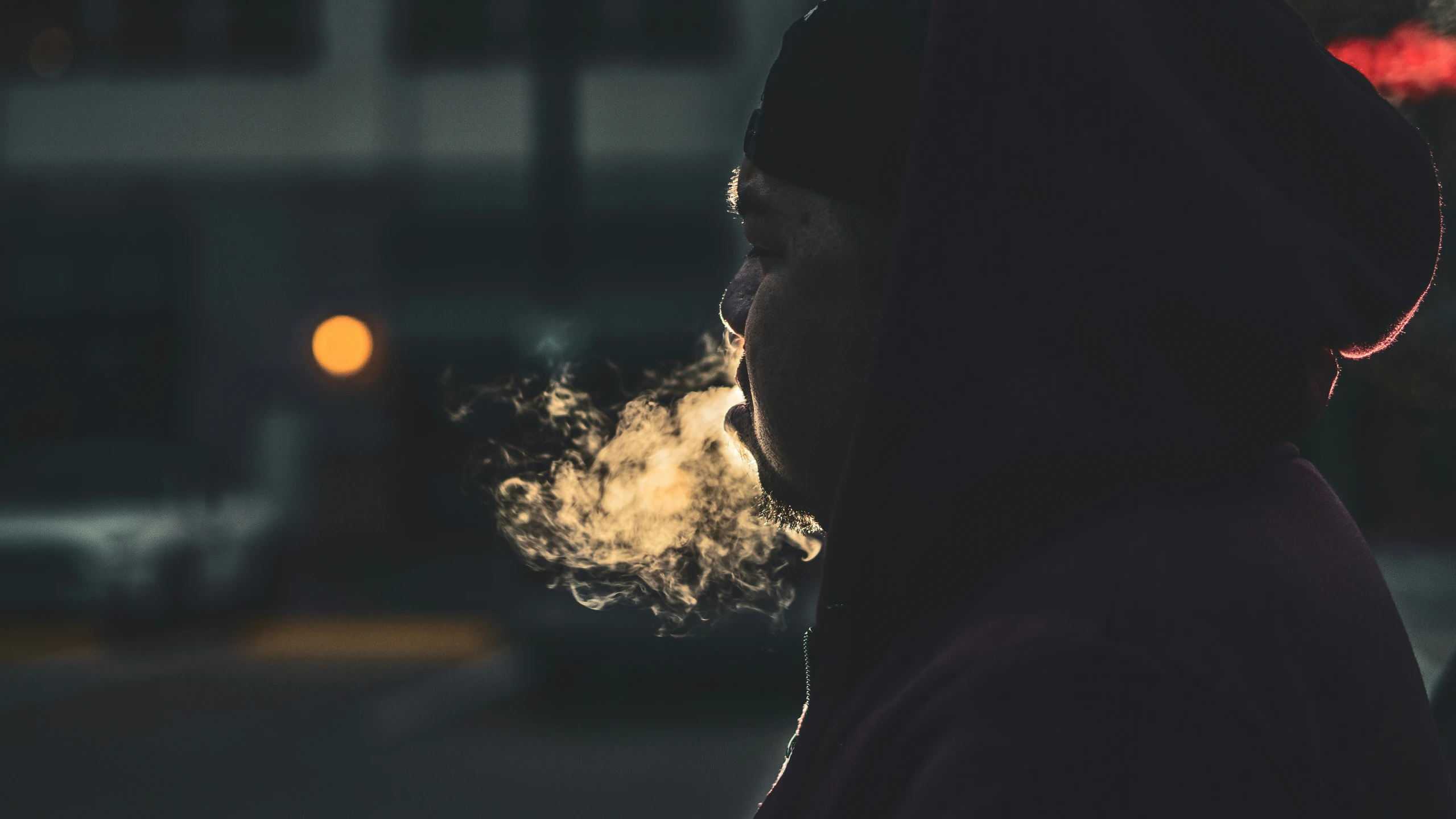 the back of a man with his head down smoking a cigarette