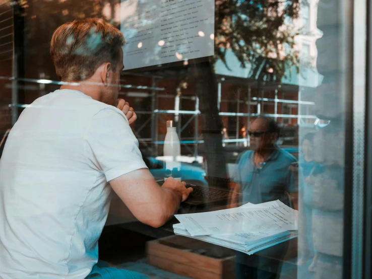 a person sitting at a table next to a window