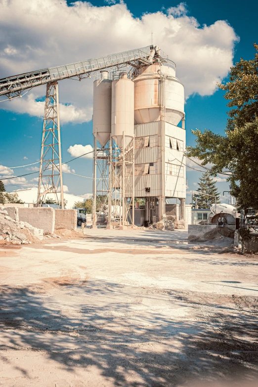 the large white grain storage building is near a tree