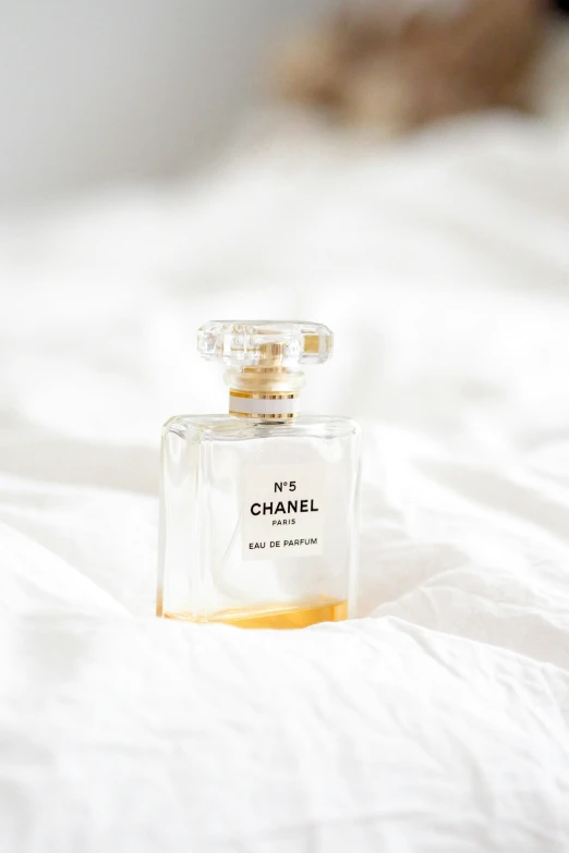 a small bottle of perfume sitting on top of a bed