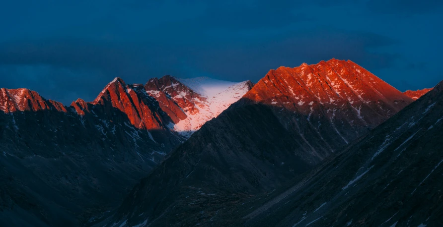 a mountain range with snow covered peaks at night