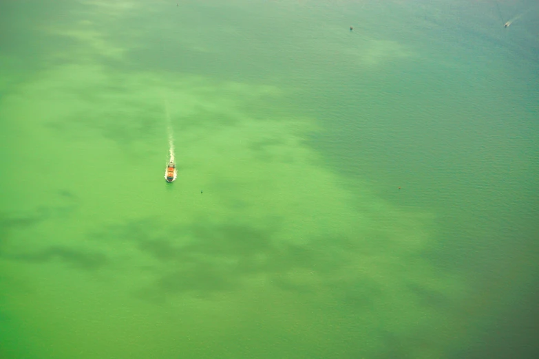 an aerial s of green waters and a small boat