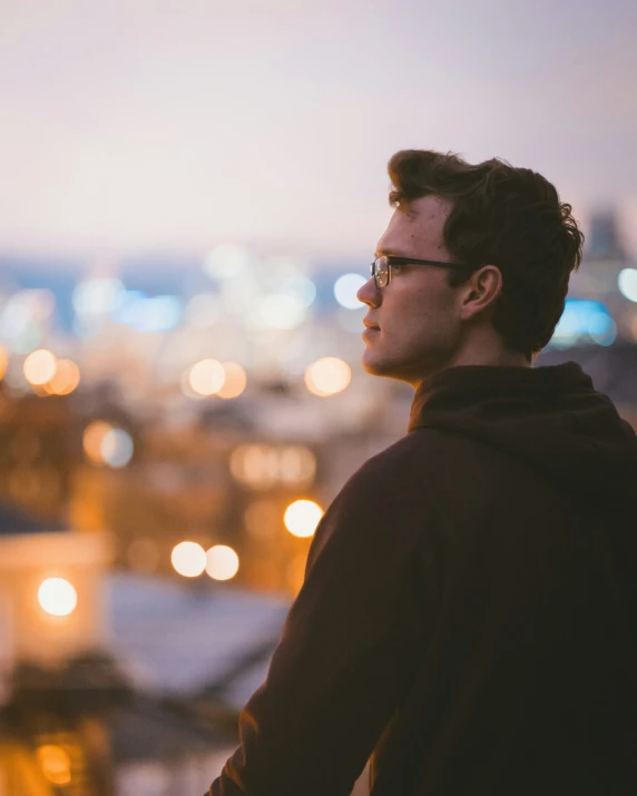 a man in a black hoodie looks over a city