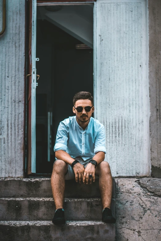 a man sitting on steps wearing sunglasses