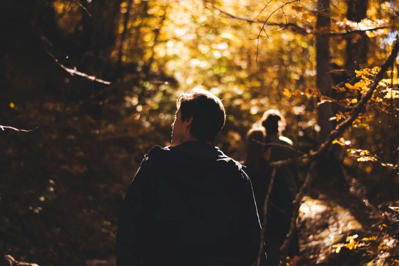 two people are hiking down a trail in the woods