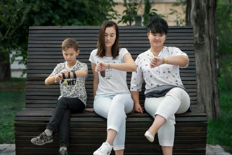 two adults and a child sitting on a wooden bench