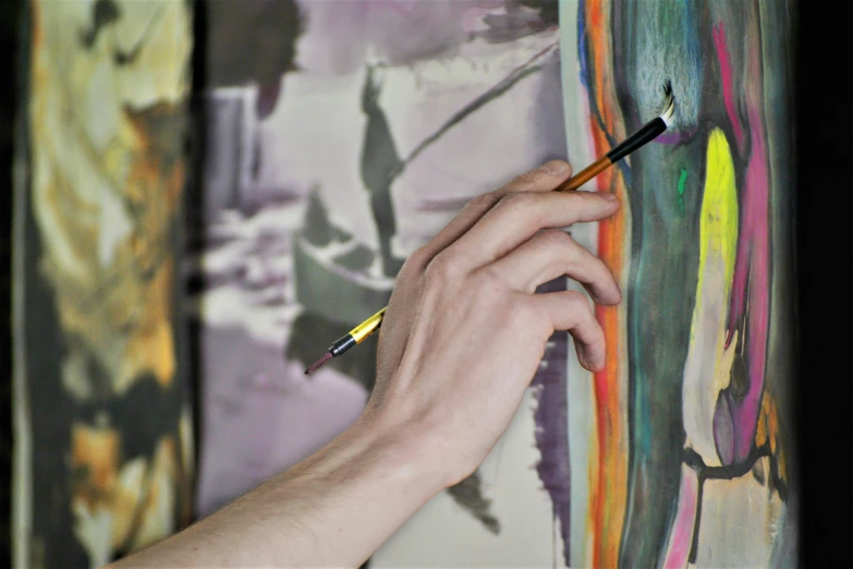 a person drawing on a piece of wall paper with paint and a yellow pencil