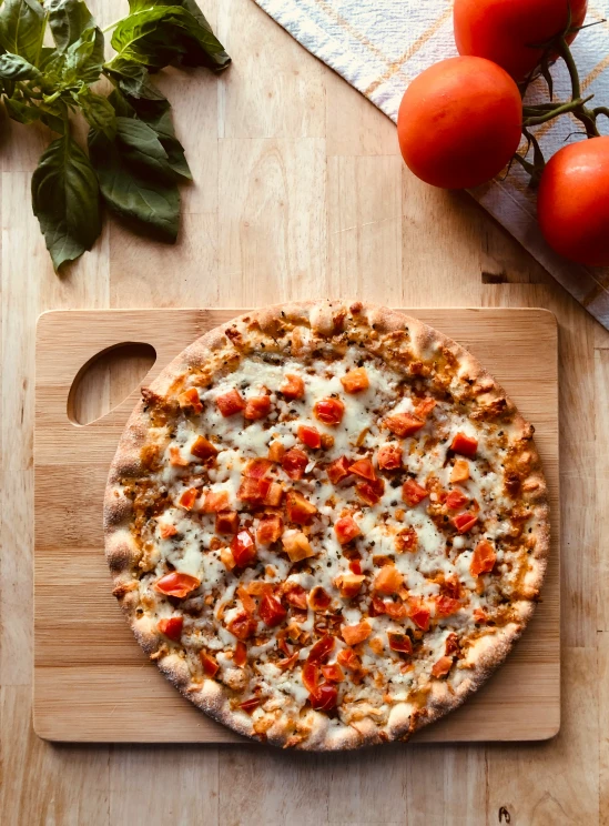 a pizza topped with meat and tomatoes next to fresh basil