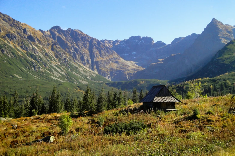 a cabin with mountains in the background on a grassy field