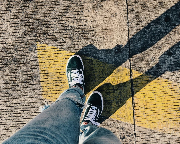 a person with sneakers on sitting by a yellow painted curb