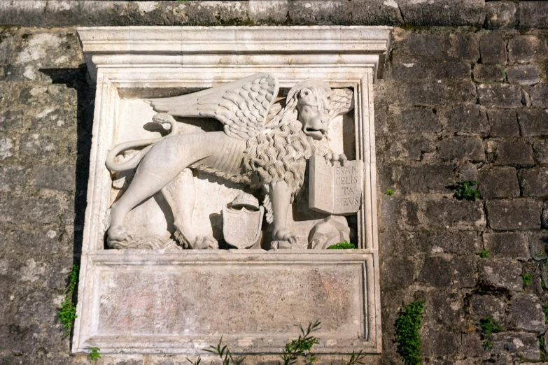 a white statue of a lion on a stone wall