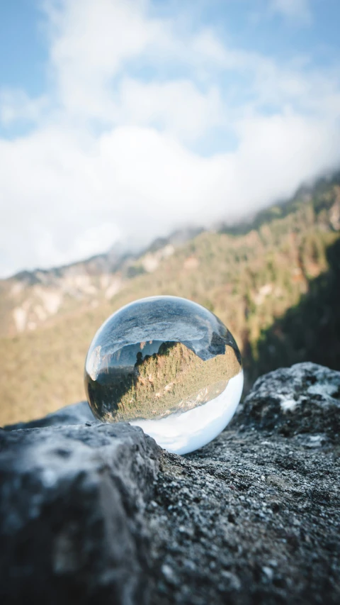 a marble ball sitting on top of a stone near a mountain