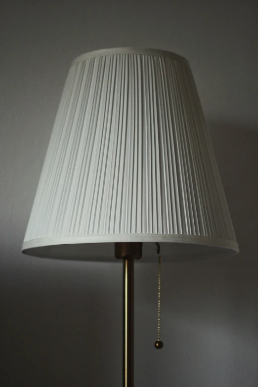 a white lampshade is against a wall