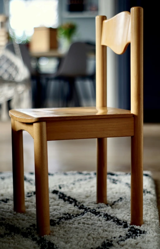 a wooden chair on a rug in front of a couch