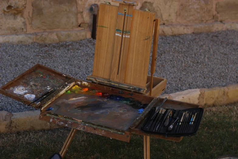 an easel and many paint is on the ground