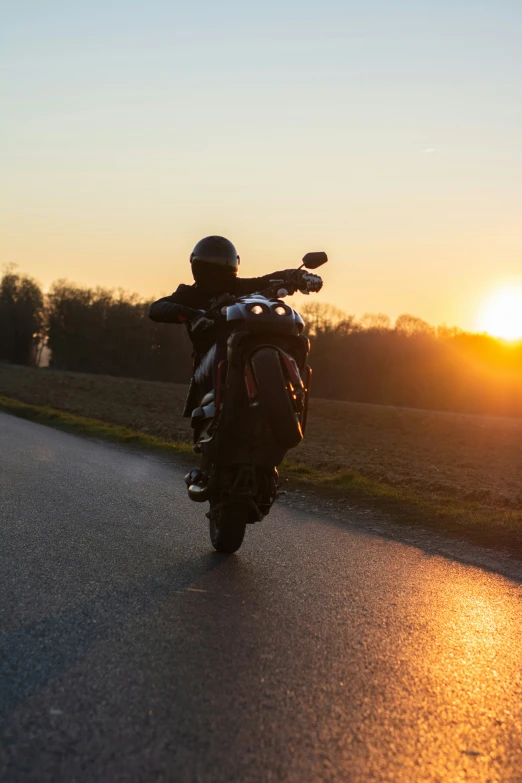a motorcycle is on the road with the sun in the background
