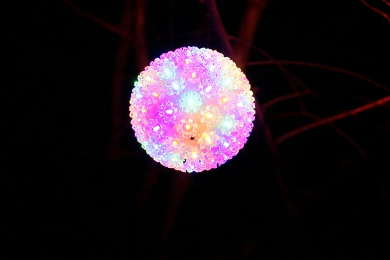 a pink and blue ball on some nches in the dark