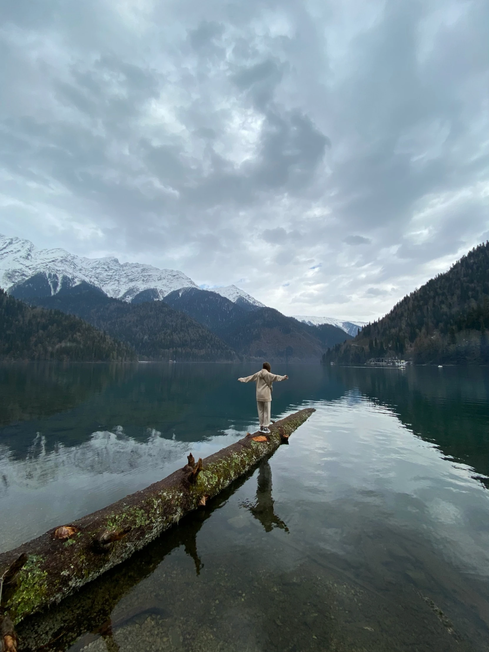 a person on a log standing on a lake