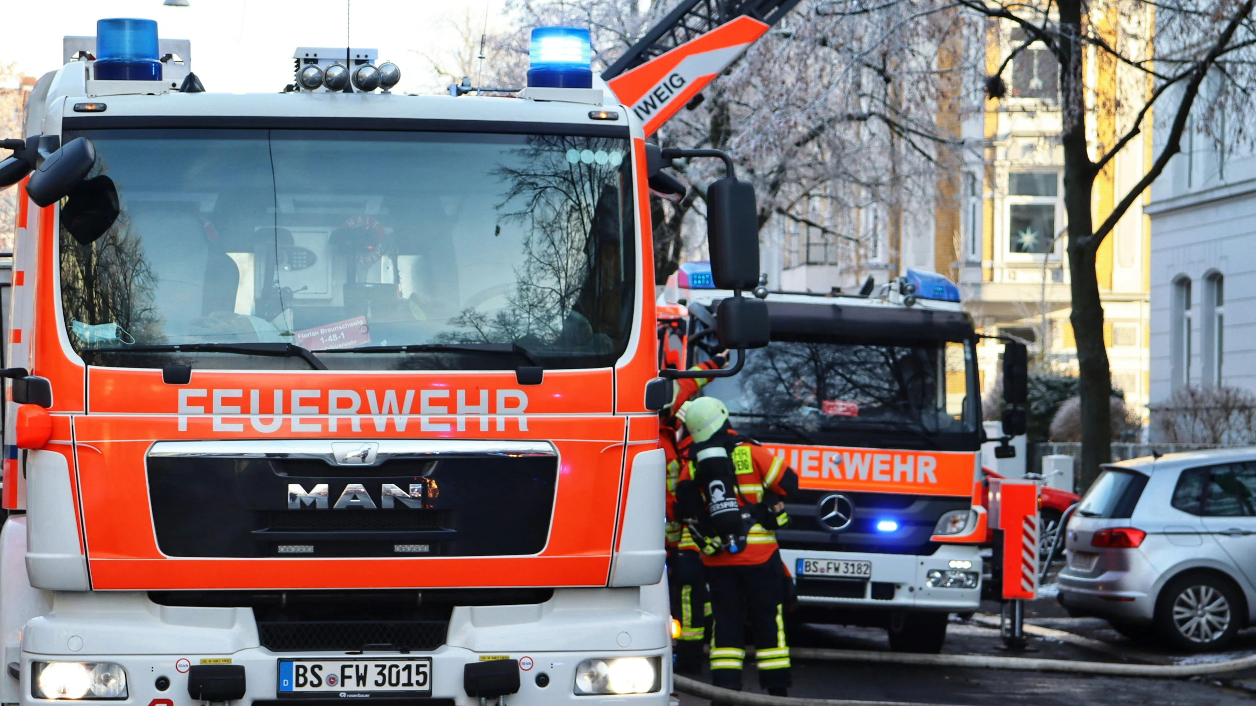 an orange truck with the name feuerwerer, parked next to two men in front of some cars