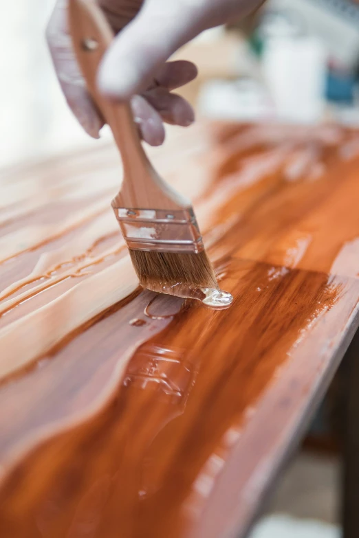 a person holding a brush to paint a wood countertop