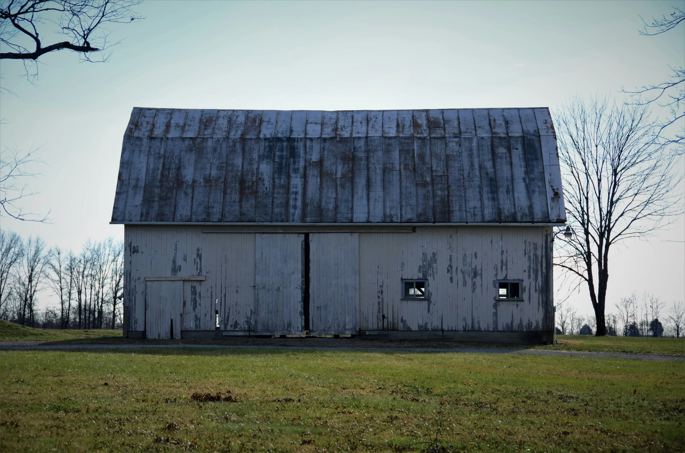 a big barn sitting on the grass next to trees