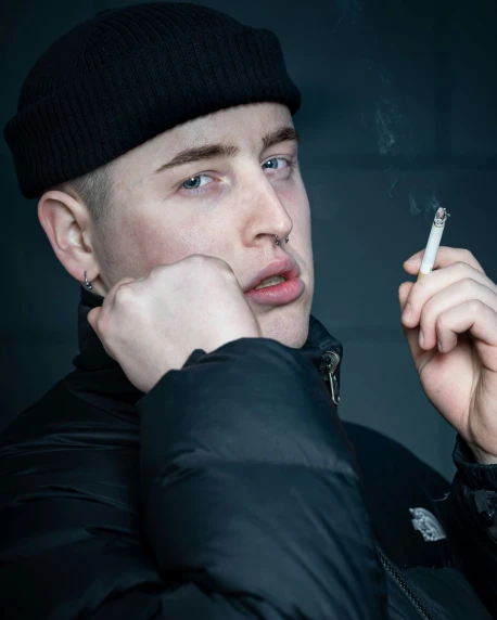 a man in a black coat smoking and looking away