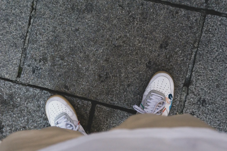 a view from above of someone's feet wearing white tennis shoes