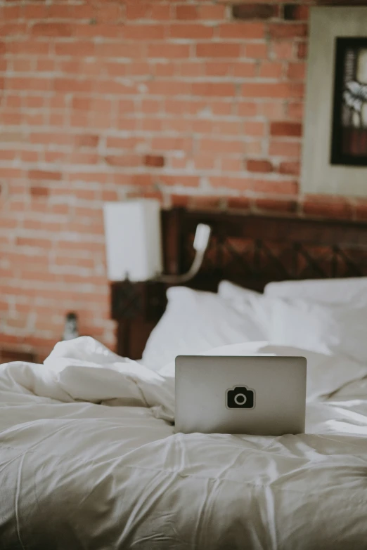 a laptop sits on a bed with white sheets and blankets
