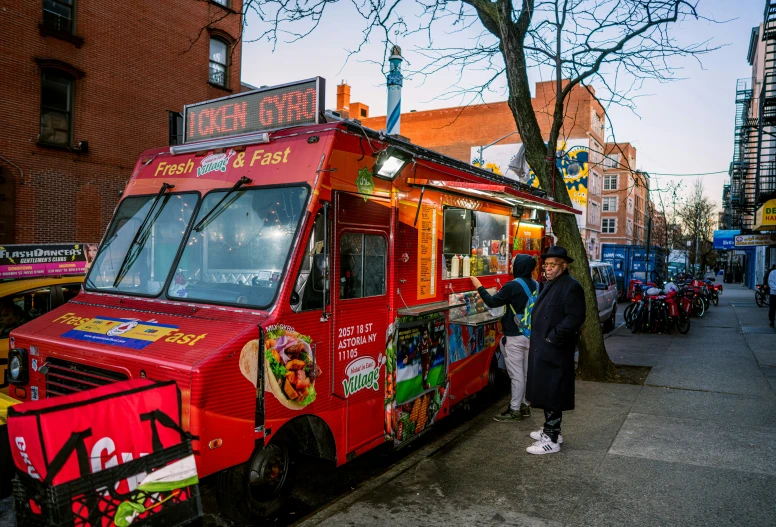 a woman standing near the food truck next to the sidewalk