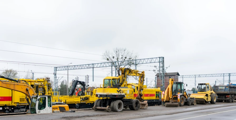 construction equipment parked alongside a rail road near buildings