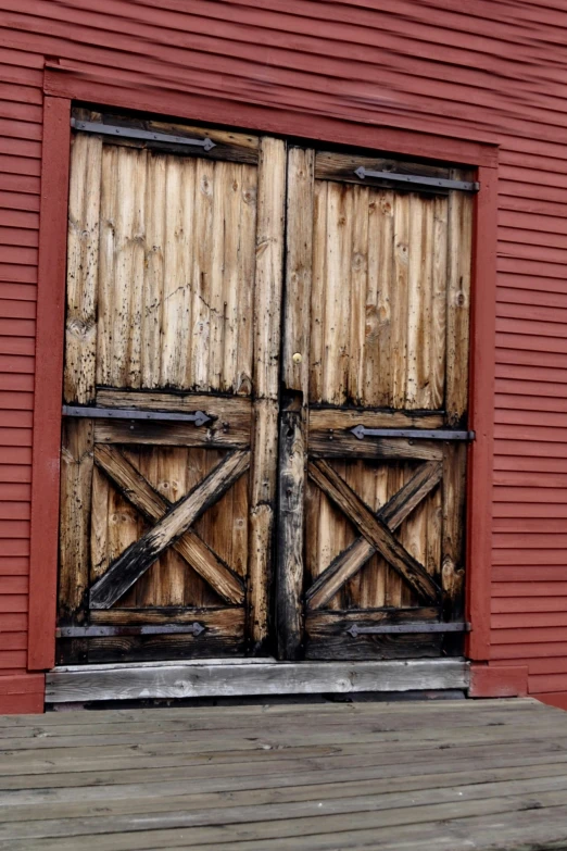 an old wooden door with wood planks and a brick building