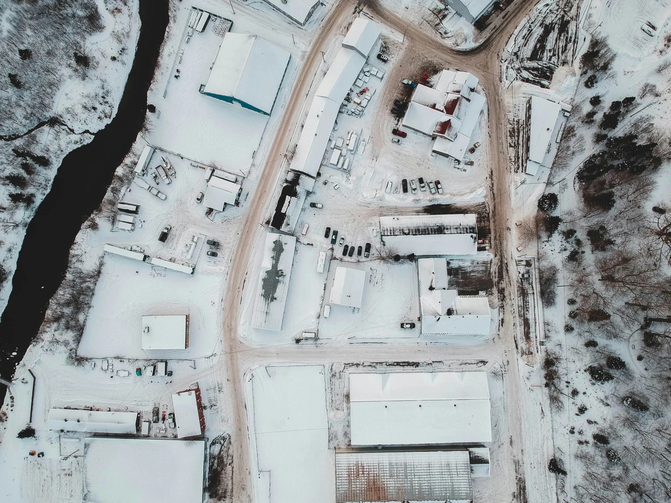 an aerial view of snow covered buildings near water