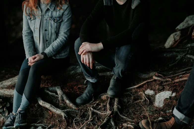 two people sitting on the ground near a tree