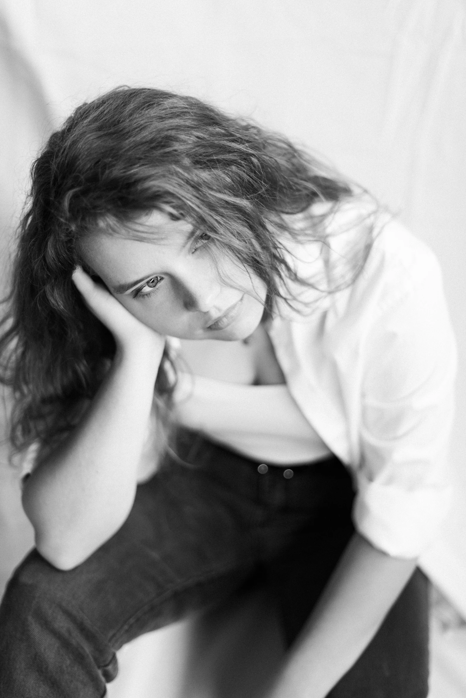 black and white portrait po of a girl leaning on a bed