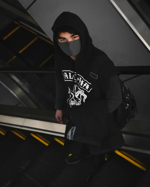 a man wearing a black mask and sweater is climbing stairs