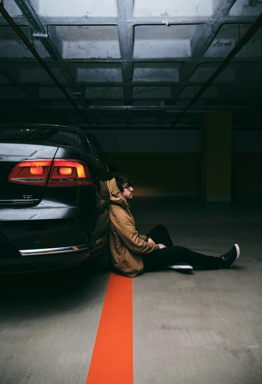 a person sitting against the back of a car